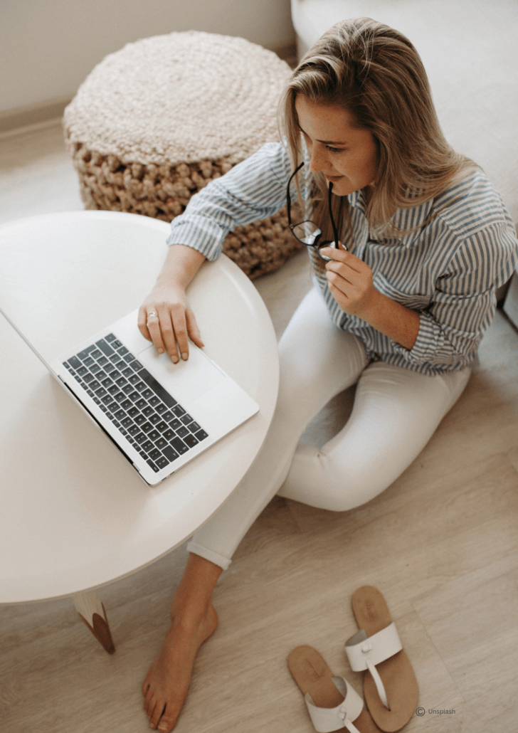 Junge Frau auf dem Boden sitzend recherchiert am Laptop